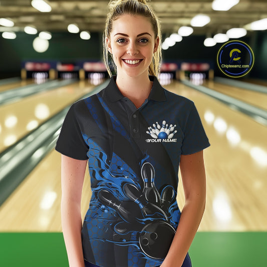 Female model at a bowling lane wearing a black and blue bowling polo shirt with fiery bowling artwork and angular stripe details.