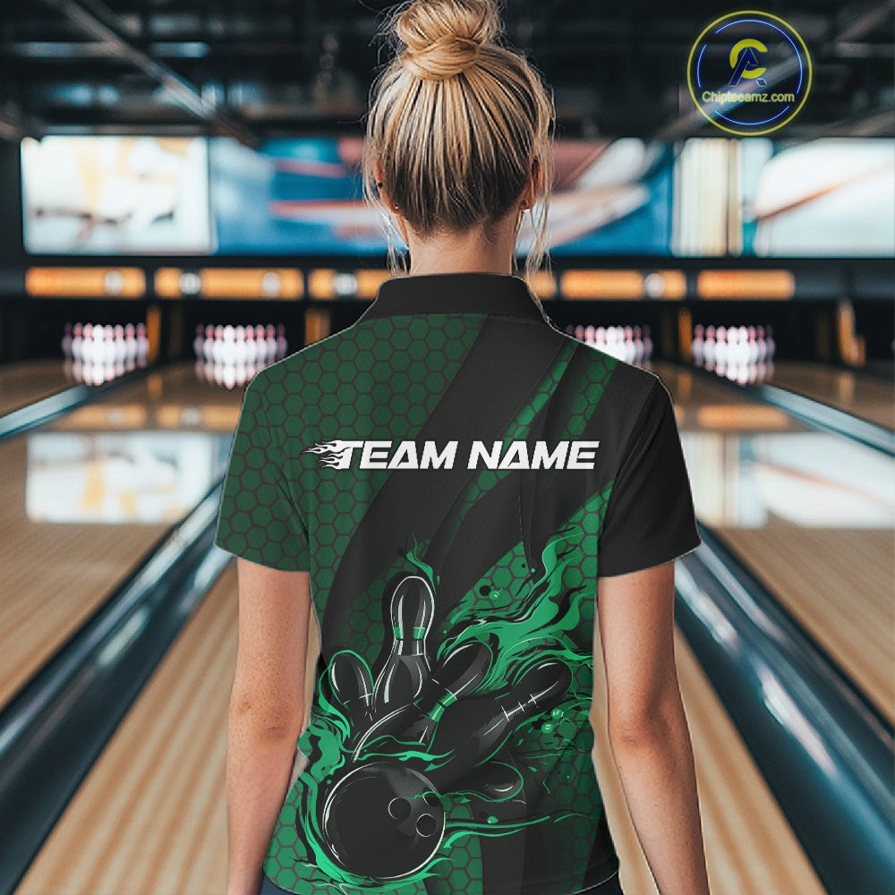 Female model in a bowling alley wearing a black and green quarter zip shirt, back view showing flaming bowling ball striking pins with hexagon pattern and diagonal stripe accents