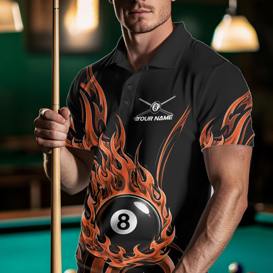 A man wearing a black polo shirt with a bold orange and brown flame graphic and a 8-ball design, holding a pool cue in a dimly lit billiards room.