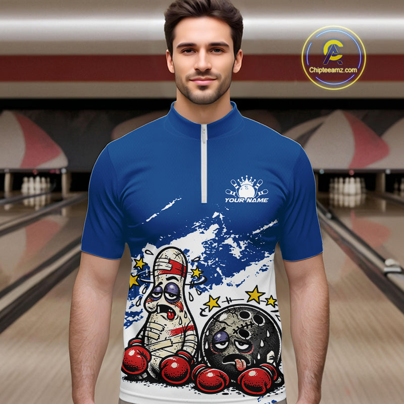 Male model at a bowling lane wearing a blue and white quarter-zip shirt, playful boxing bowling ball and pin artwork with sporty energy.
