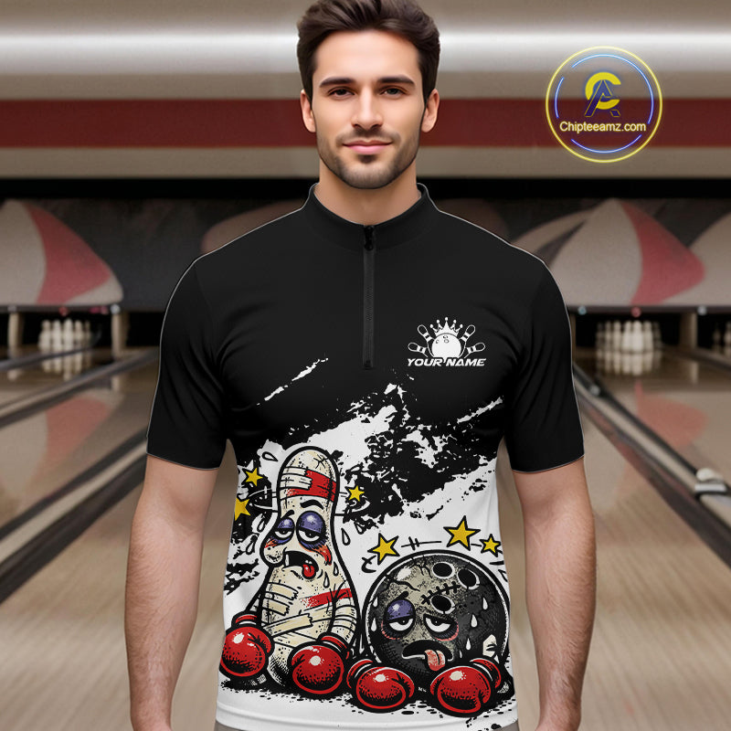 Male model at a bowling lane wearing a black and white quarter-zip shirt, humorous boxing bowling ball and pin artwork with bold contrast.