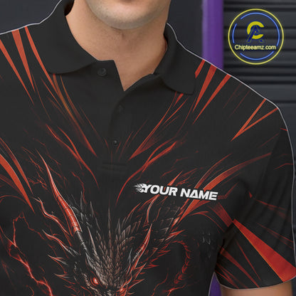 A man wearing a black short-sleeve bowling-themed polo shirt with a red and orange dragon graphic and bowling pins and ball design, standing in a bowling alley holding a bowling ball.