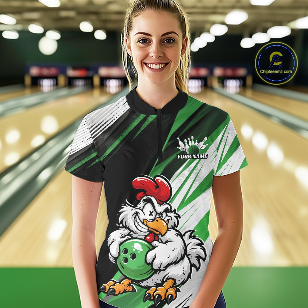 A woman wearing a custom bowling shirt with a cartoon rooster holding a bowling ball, set against a blurred bowling alley background. The shirt features green, black, white, and red colors with a custom name printed on the chest.