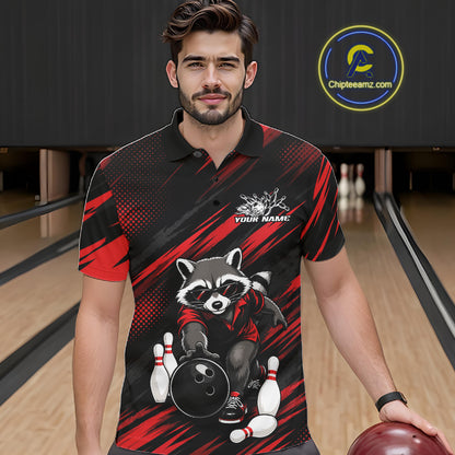 A man wearing a black and red bowling-themed polo shirt with a raccoon graphic, standing in a bowling alley holding a bowling ball. 