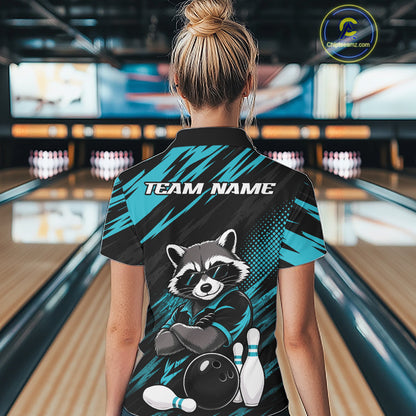 A woman viewed from behind wearing a bowling-themed short-sleeve polo shirt in a bowling alley. The back of the shirt features a raccoon graphic with bowling pins and ball, the text 'TEAM NAME', and a teal and black patterned design.