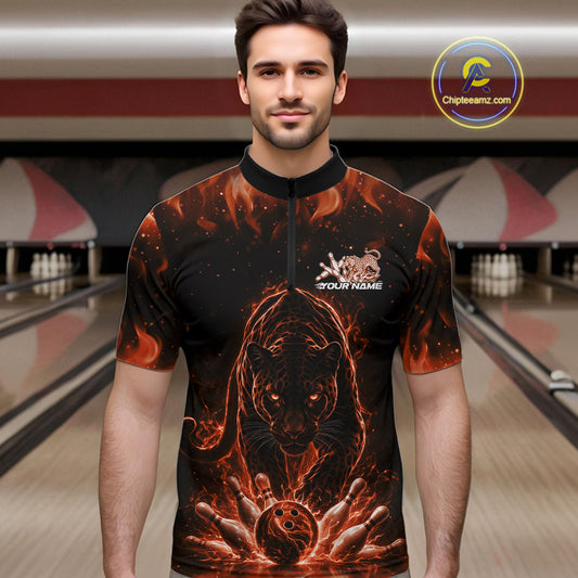 Front view of a male model in a bowling lane wearing a black quarter-zip shirt with glowing orange electric panther and dynamic bowling strike graphics.