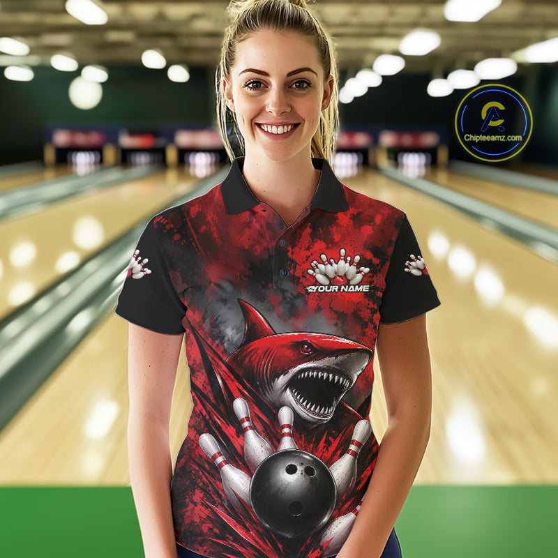 Woman wearing a red and black bowling shirt with a shark design in a bowling alley.