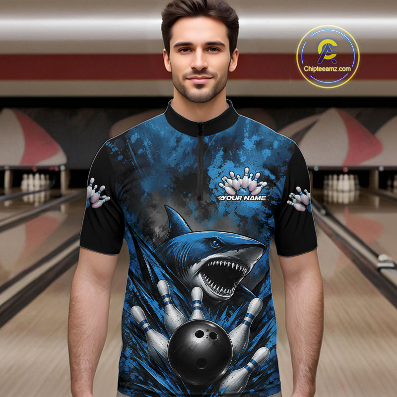 Man wearing a blue and black bowling shirt with shark design in a bowling alley.