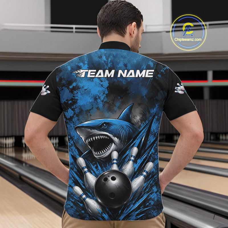Person wearing a blue and black bowling shirt with a shark design in a bowling alley.