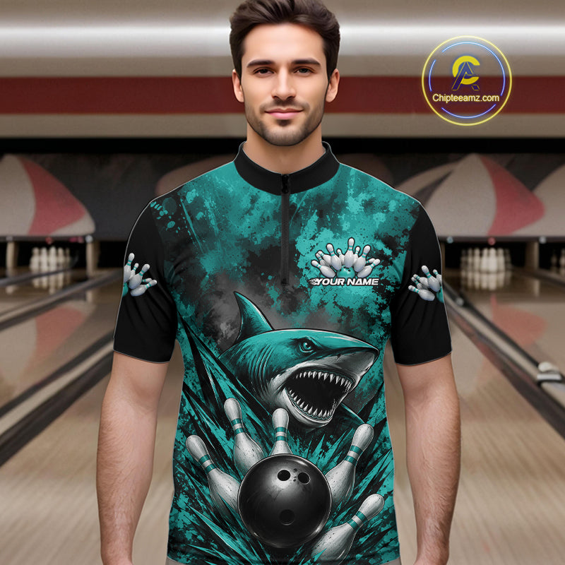 Man wearing a teal and black bowling shirt with a shark design in a bowling alley.