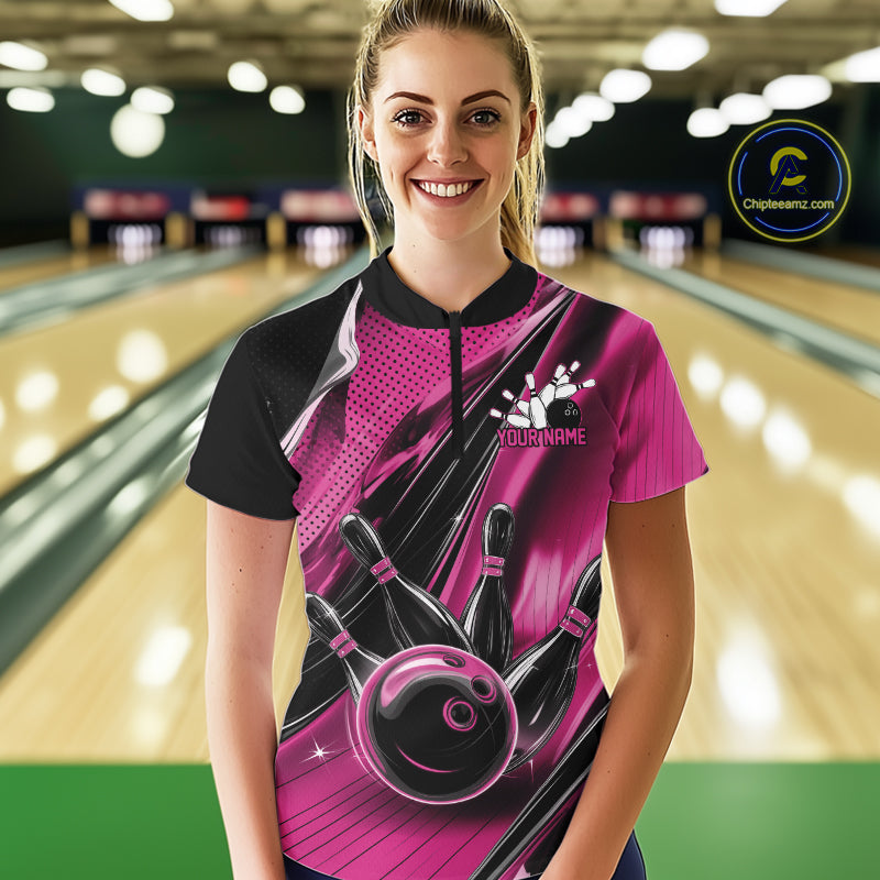 Female model wearing a black and pink bowling quarter-zip shirt at the bowling lane with fast-moving bowling strike graphics.