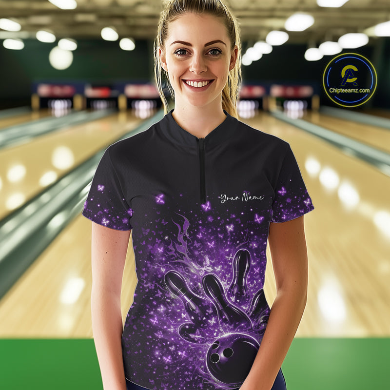 Female model in a black and purple bowling quarter-zip shirt at the lane with fiery bowling strike graphics.