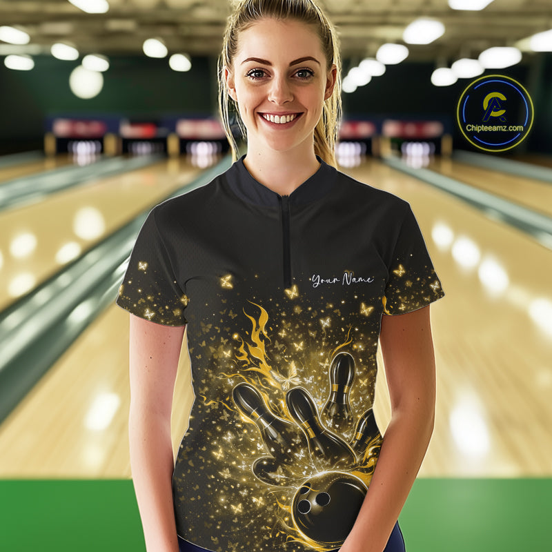 Female model wearing a black and yellow bowling quarter-zip shirt at the bowling lane with flaming bowling strike artwork and sparkly butterflies.