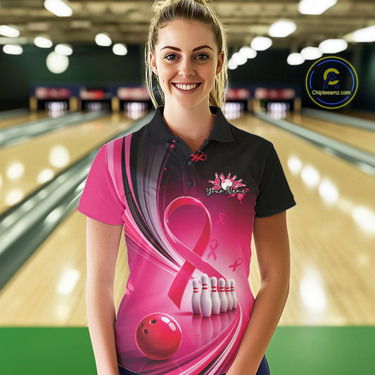 Female model in a black and pink bowling polo with breast cancer awareness ribbons and bowling artwork, front view inside a bowling alley