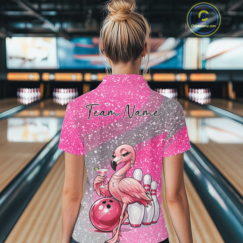 Back view of a female model in a bowling alley wearing a pink quarter-zip bowling shirt featuring an elegant flamingo beside a bowling ball.