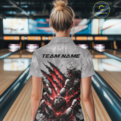 Back view of a female model wearing a gray bowling quarter zip shirt featuring a dramatic red bowling ball striking pins graphic with claw-mark artwork in a bowling lane.