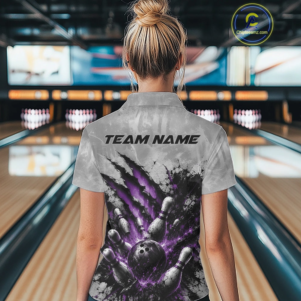 Back view of a female model wearing a gray bowling quarter zip shirt showcasing a dramatic purple bowling ball and pins graphic with claw-mark artwork in a bowling lane.