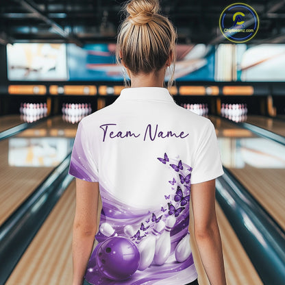 Female model wearing a white and purple bowling polo with butterfly artwork and bowling graphics, back view at the bowling lane