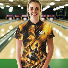 Load image into Gallery viewer, Front view of a female model wearing a bowling quarter zip shirt with a black and gold bowling ball hitting the pins graphic accented by flowing metallic ribbons at a bowling lane.