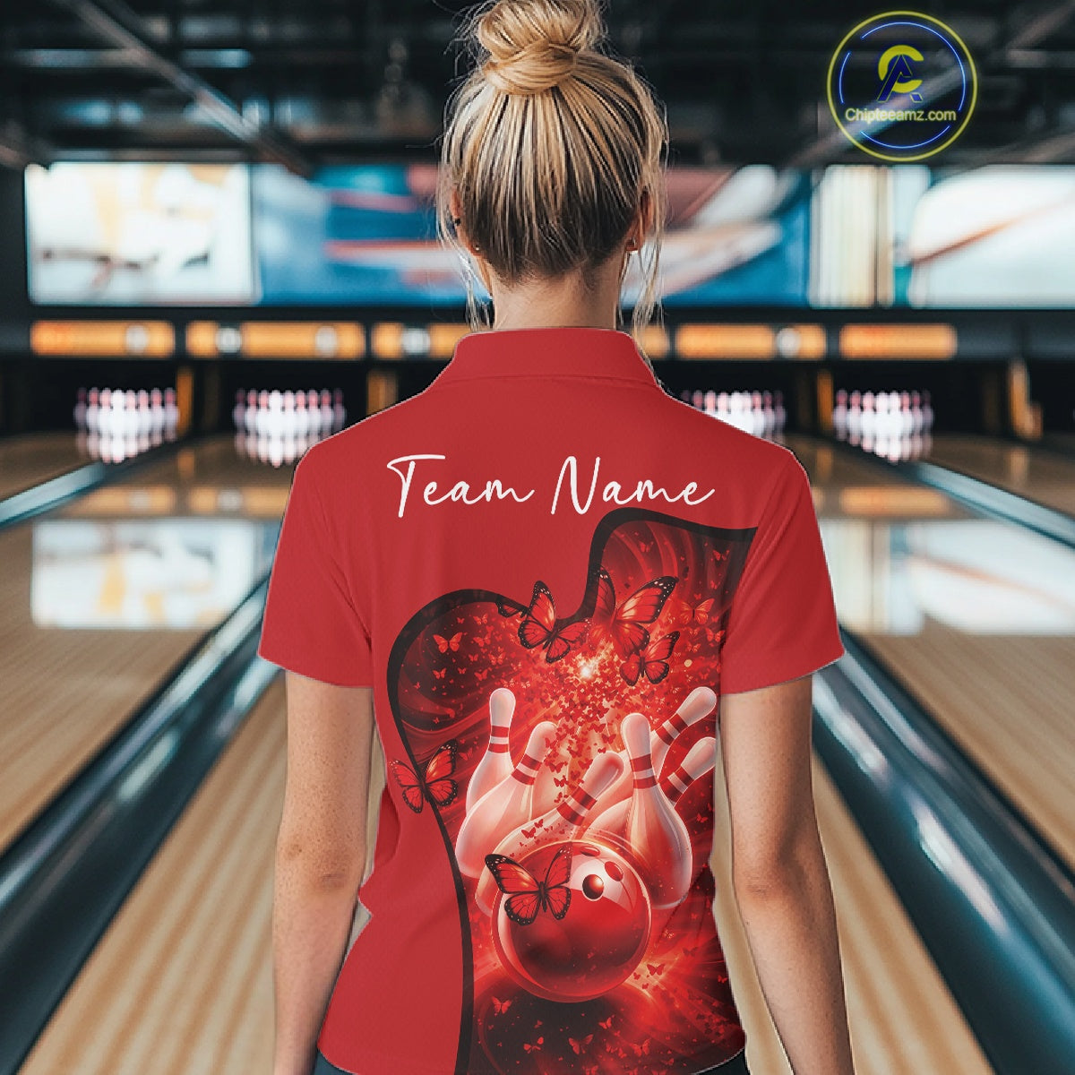 Person wearing a red butterfly bowling shirt with a design and 'Team Name' text in a bowling alley.
