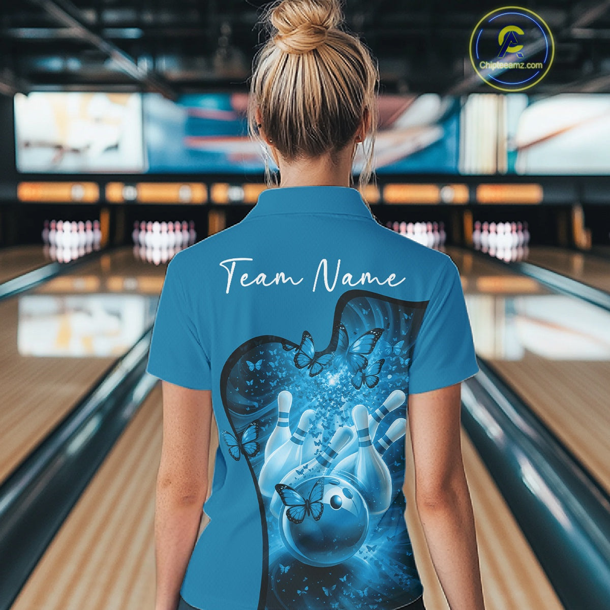 Back view of a female model in a blue bowling quarter zip showcasing butterfly graphics and bowling-themed artwork