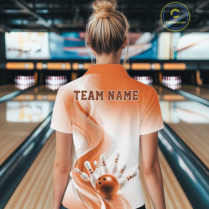 Back view of a female model wearing a white and orange bowling polo shirt with flowing wave artwork and a bowling strike graphic in a bowling alley