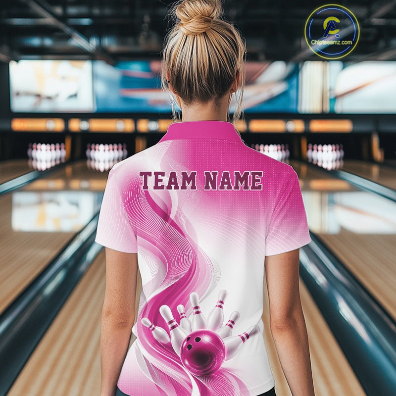 Female model in a bowling alley displaying the back of a white and pink bowling quarter-zip shirt with bowling action artwork