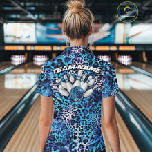 Load image into Gallery viewer, Back view of a woman standing at a bowling alley, wearing a blue, teal, and black leopard-print bowling polo with “Team Name” and bowling pins on the back.