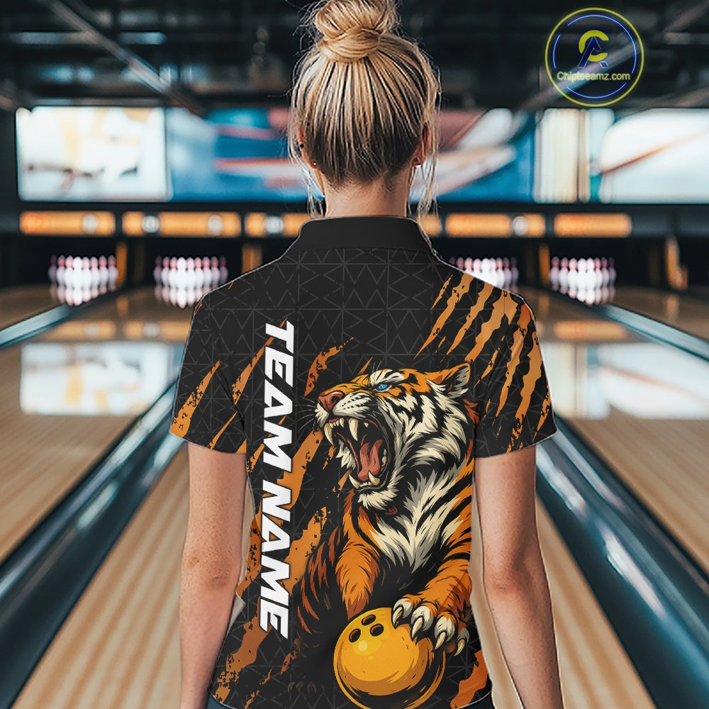 Back view of a female model wearing a black and yellow bowling quarter-zip shirt in a bowling lane, featuring a roaring tiger holding a yellow bowling ball with orange claw-stripe graphics and a geometric background pattern.