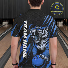 Load image into Gallery viewer, Back view of a male model in a bowling lane wearing a black and mid blue bowling polo shirt featuring a roaring tiger holding a mid blue bowling ball with coordinated claw-stripe graphics and a geometric background pattern.