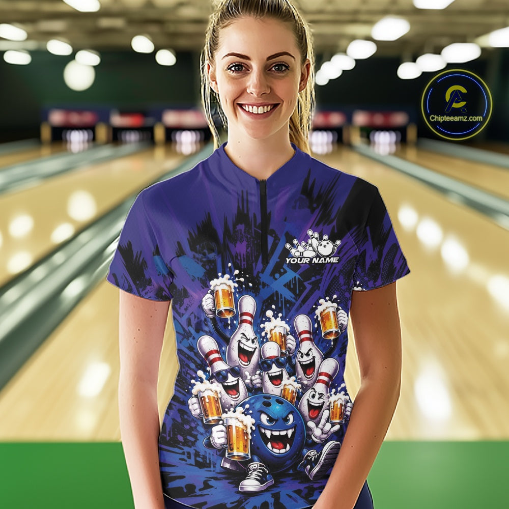 Front view of a female model at a bowling lane wearing a blue and purple bowling quarter-zip shirt featuring funny bowling pins and a bowling ball holding frothy beer mugs in a playful bowling-themed illustration.