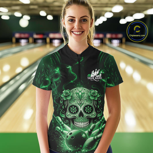 Female model wearing a black and green bowling quarter-zip shirt at a bowling lane with floral sugar skull artwork and bowling-themed graphics.