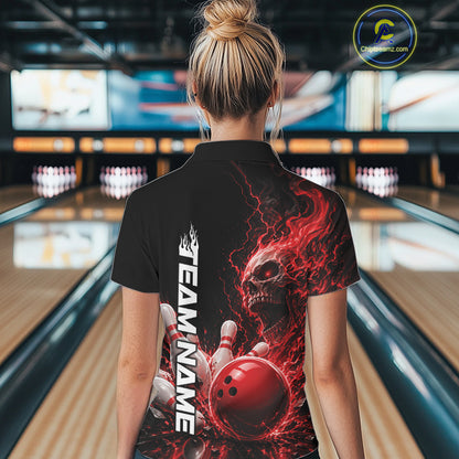 Back view of a female model in a bowling alley wearing a black bowling polo shirt featuring a red fiery skull with lightning striking a bowling ball and pins and a custom name.
