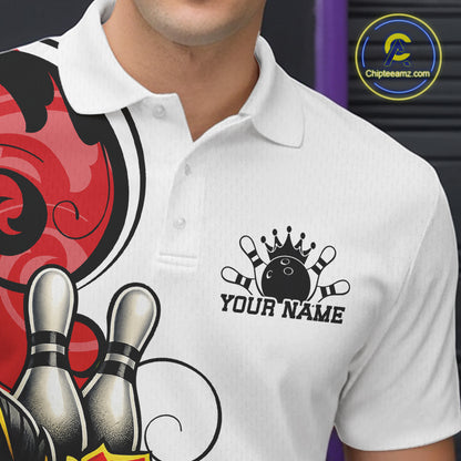 A close-up of a white short-sleeve polo shirt worn by a person, featuring a black bowling-themed chest graphic with a crown, bowling pins, and the text 'YOUR NAME'. 