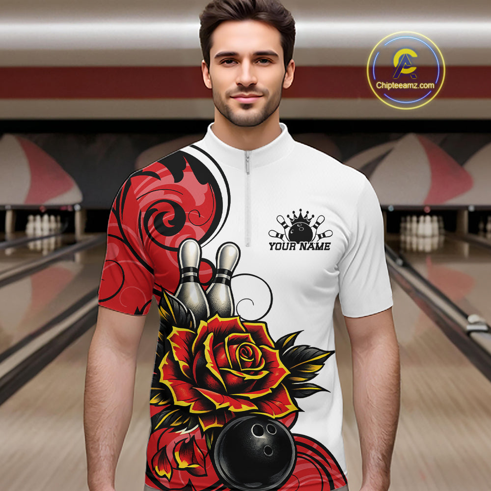A man wearing a white short-sleeve bowling quarter zip shirt with a red and black tattoo-style floral and bowling pin graphic, standing in a bowling alley. 