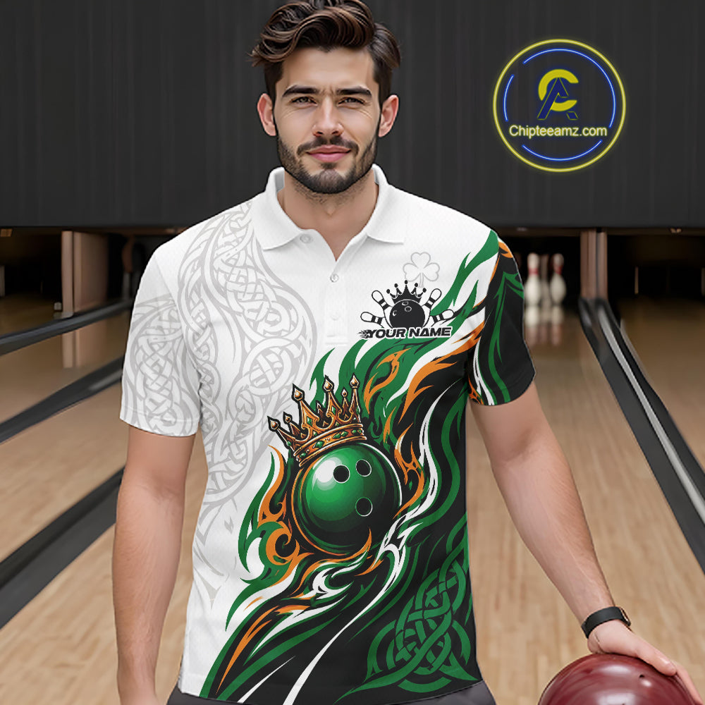 A man wearing a white short-sleeve polo shirt with a green, black, and orange bowling-themed graphic print, standing in a bowling alley and holding a bowling ball. 