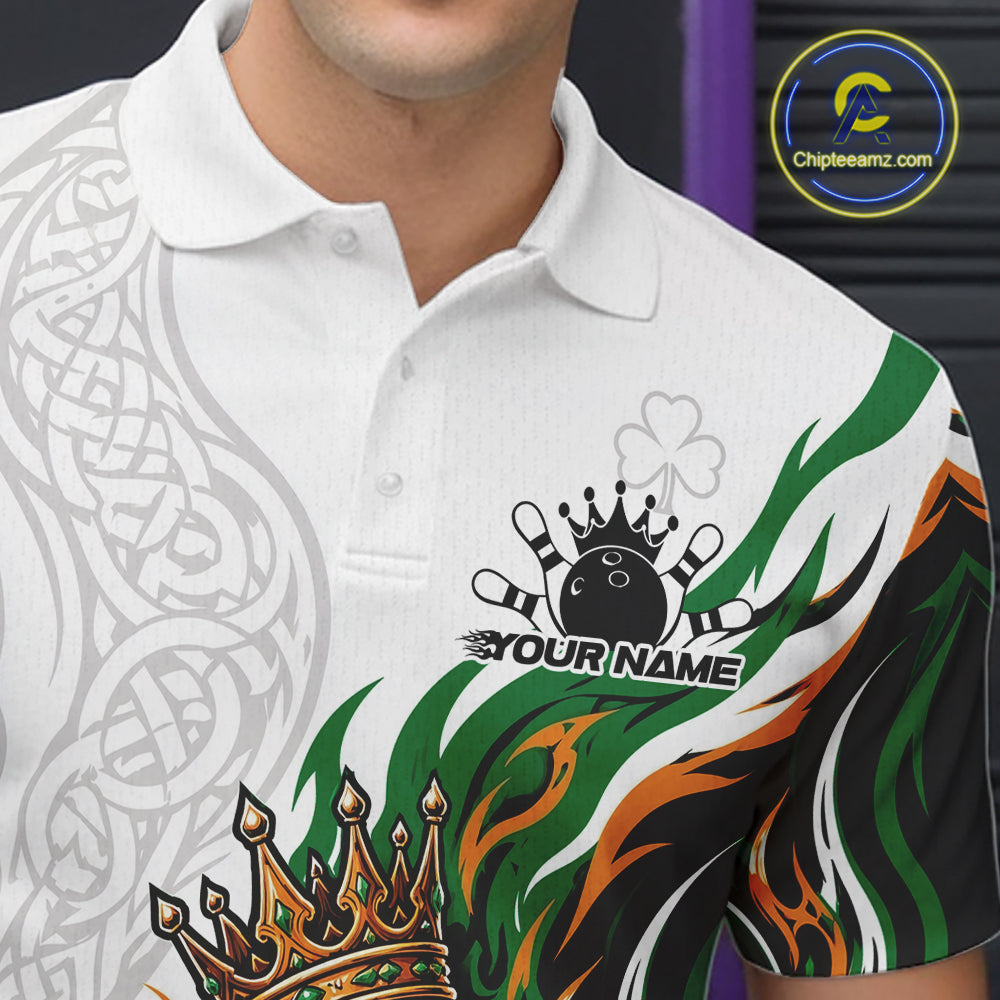 A close-up of a white short-sleeve polo shirt with a custom graphic design. The design features a black bowling ball and pins with a crown, the text 'YOUR NAME', a shamrock, and green, orange, and black flame-like patterns.