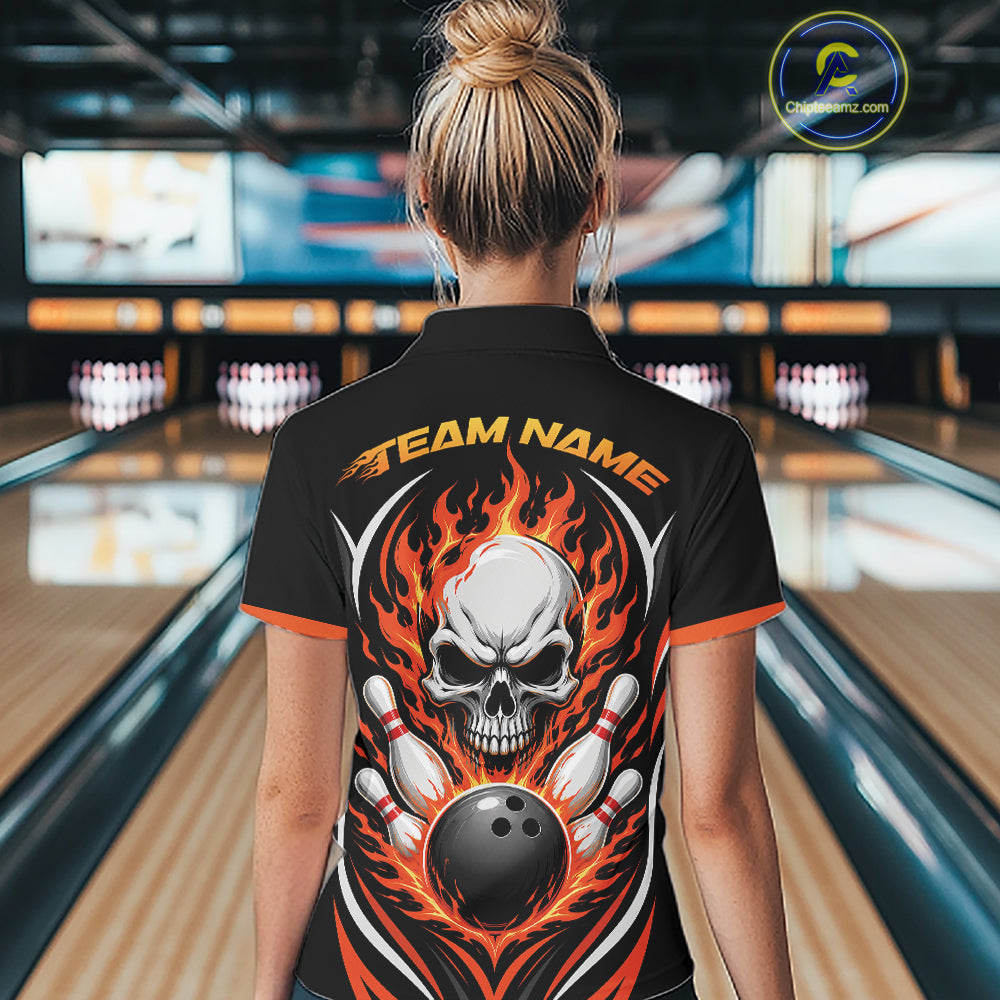 A woman viewed from behind wearing a black bowling-themed short-sleeve quarter zip shirt with a large skull, bowling pins, and orange flames graphic on the back, standing in a bowling alley.