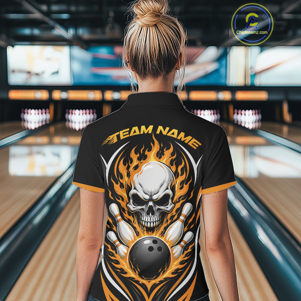 A woman viewed from behind wearing a black bowling-themed short-sleeve shirt with a large skull, flame, and bowling ball graphic on the back, standing in a bowling alley.