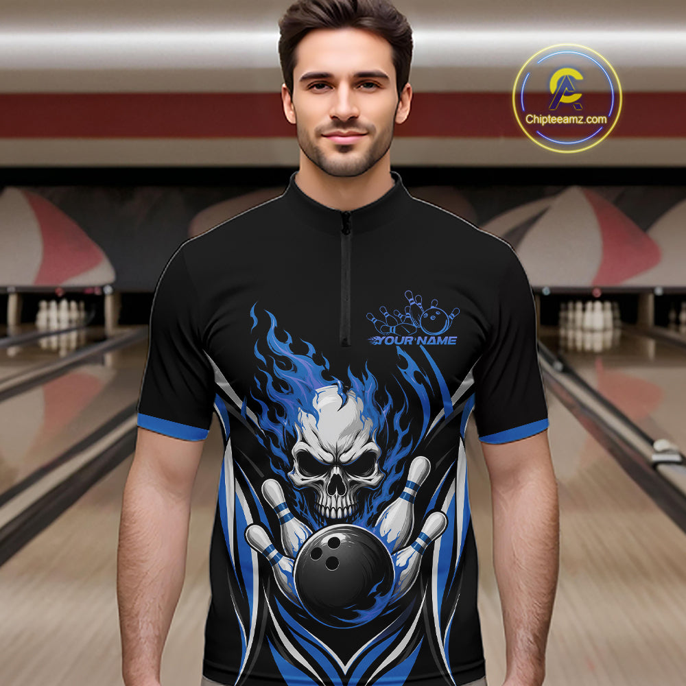 A man wearing a black short-sleeve bowling quarter zip shirt jersey with a blue and white skull-and-bowling-ball flame graphic, standing in a bowling alley.
