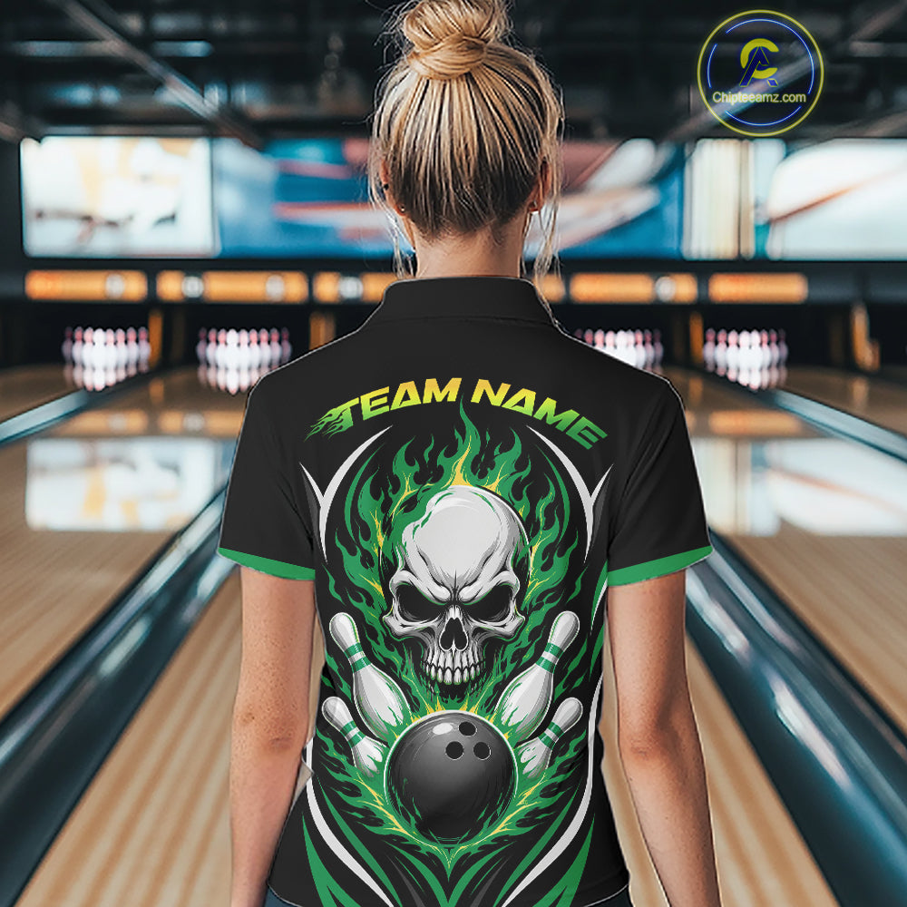 A woman viewed from behind wearing a black short-sleeve bowling shirt with a large skull and flame graphic on the back, standing in a bowling alley. 