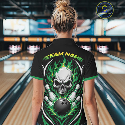 A woman viewed from behind wearing a black short-sleeve bowling shirt with a large skull and flame graphic on the back, standing in a bowling alley. 