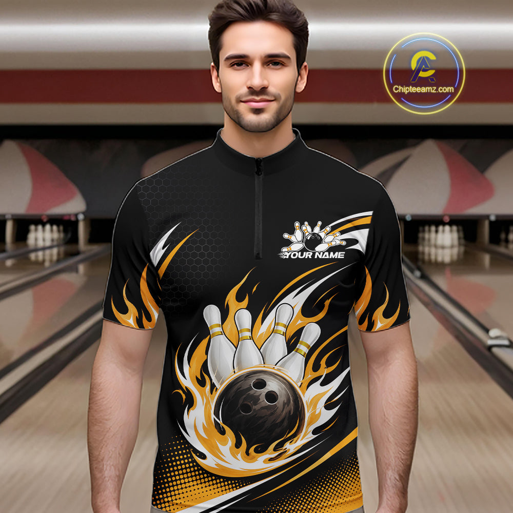 A man wearing a black short-sleeve bowling quarter zip shirt with a flame and bowling pin design, standing in a bowling alley. 