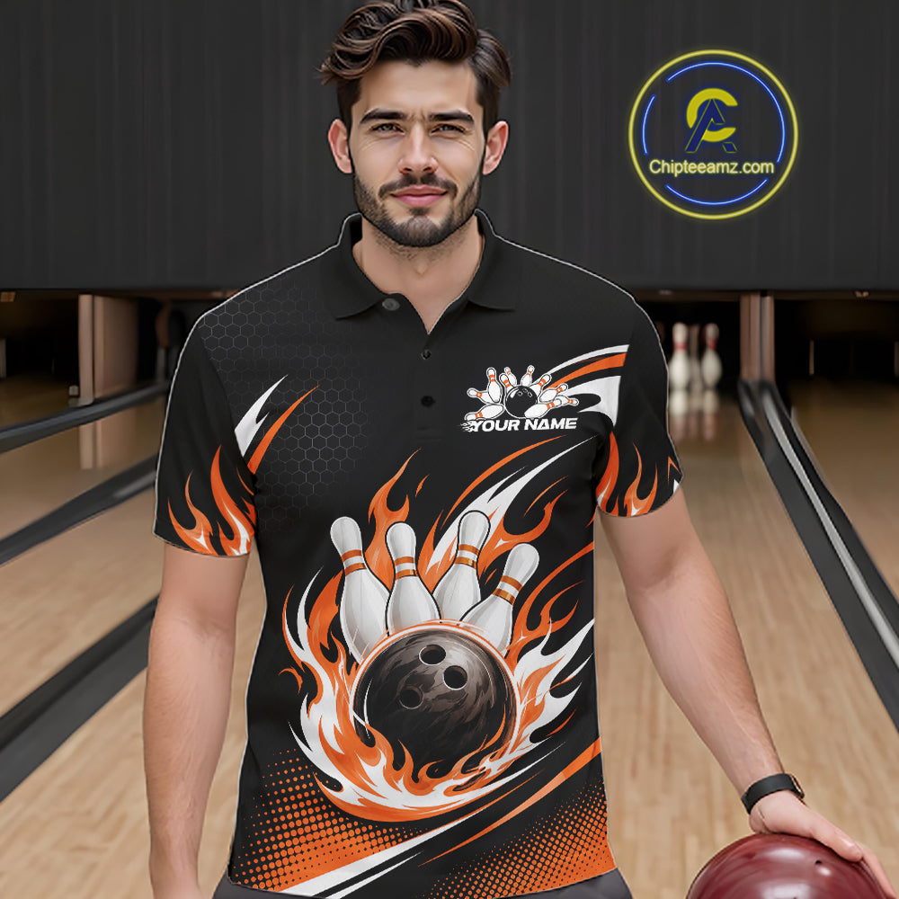 A man wearing a black short-sleeve bowling polo shirt with a large graphic of a bowling ball and flames, standing in a bowling alley. 