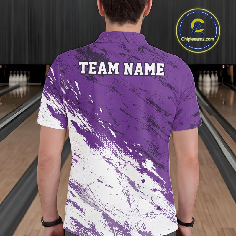 Back view of a male model in a bowling alley wearing a bowling polo shirt featuring a white and purple paint splatter distressed sportswear design.
