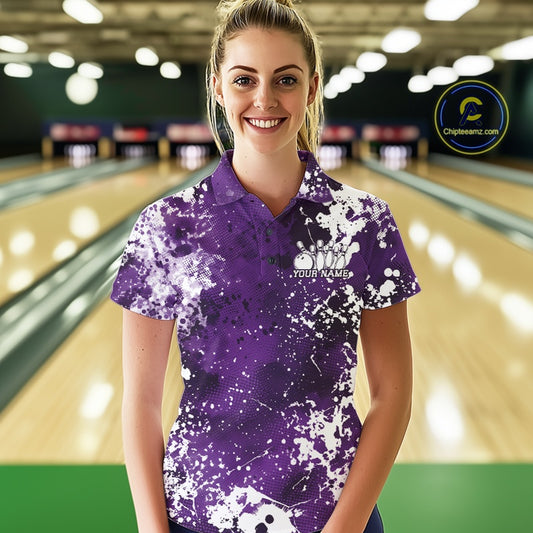 Front view of a male model in a bowling alley wearing a bowling polo shirt featuring a white paint splatter design on a blue sportswear shirt.
