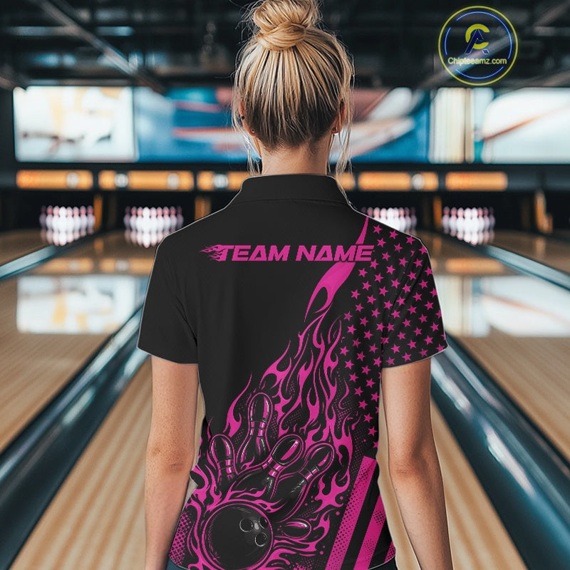 Back view of a female model in a bowling venue wearing a black quarter-zip shirt featuring pink flame bowling artwork and flag-inspired details.
