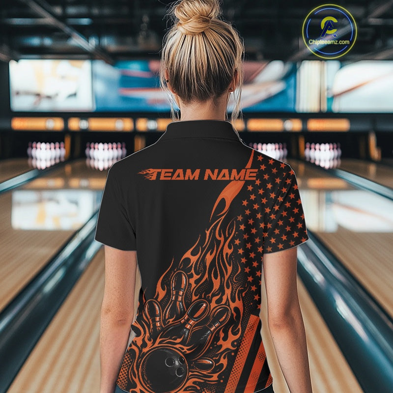 Back view of a female model in a bowling alley wearing a black quarter-zip shirt featuring a flaming bowling strike graphic with patriotic accents.