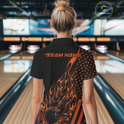 Back view of a female model in a bowling alley wearing a black quarter-zip shirt featuring a flaming bowling strike graphic with patriotic accents.
