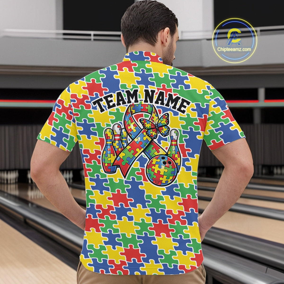 In A Bowling Lane, Front View, Male Model Wearing A Quarter-Zip Bowling Shirt Featuring Seamless Multicolored Puzzle Piece Pattern In Red, Blue, Green, Yellow Tones